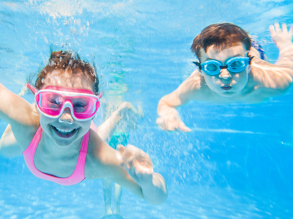 Children swimming underwater in a pool, enjoying a refreshing and playful moment